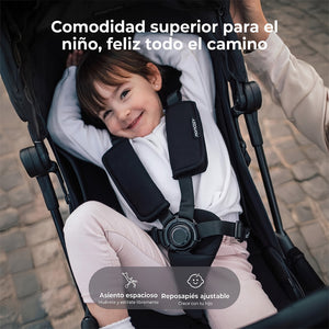 Niño sonriente paseando en el coche Momcozy TuckGo — asiento espacioso 34×50 cm con reposapies ajustable y arnés de 5 puntos