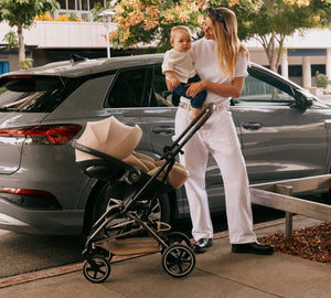 Coche de paseo eezy s twist 2 plus 2 cybex con silla de auto nido cybex en modo travel system mujer con bebé en brazos junto al auto
