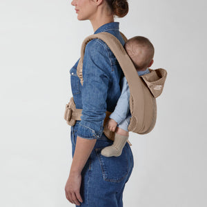 Portabebé Coÿa color Cozy Beige - vista lateral con bebé en posición frente al cuidador