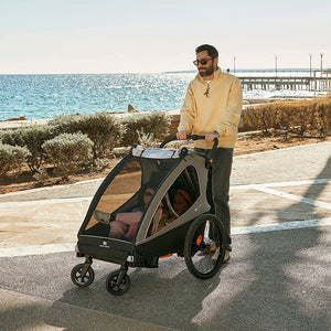 Padre empujando el Nava Walk 2 en 1 Kinderkraft en modo coche de paseo con dos niñas sentadas en su interior