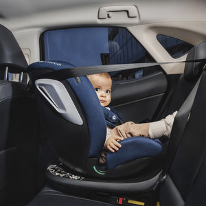 Bebé instalado en la silla de auto Kinderkraft I-GROW 2 PLUS en el asiento trasero de un vehículo, sujeto con el arnés y el respaldo lateral reforzado