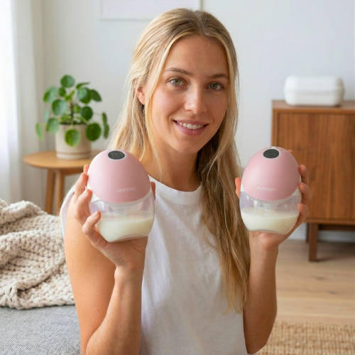 mujer sosteniendo extractor de leche m9  de momcozy en cada mano 