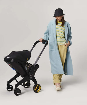mujer junto a travel system doona+ silla de auto convertible en coche para bebé
