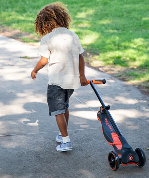 niño pequeño caminando tirando de una mano scooter con plataforma extensible smartrike