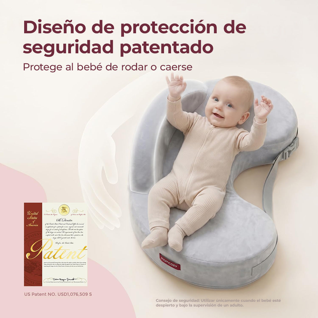 Bebé sonriendo con los brazos arriba, recostado en un cojín de lactancia Momcozy gris con diseño de protección que evita que ruede o se caiga, junto al certificado de patente