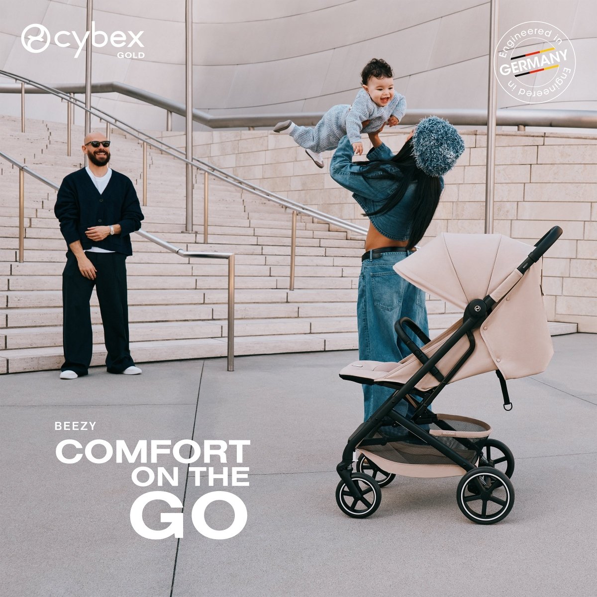 mujer alzando en sus brazos a bebé junto a coche de paseo beezy 2026 almond beige de cybex