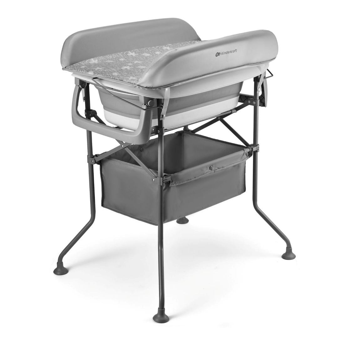 Vista angular trasera de la BUBBLY en configuración completa: mudador acolchado gris claro con estampado de estrellas y logo Kinderkraft en la parte superior, bañera blanca y gris encajada debajo, estructura metálica gris oscuro de cuatro patas con pies antideslizantes y cesta de tela gris en el nivel inferior- vista principal