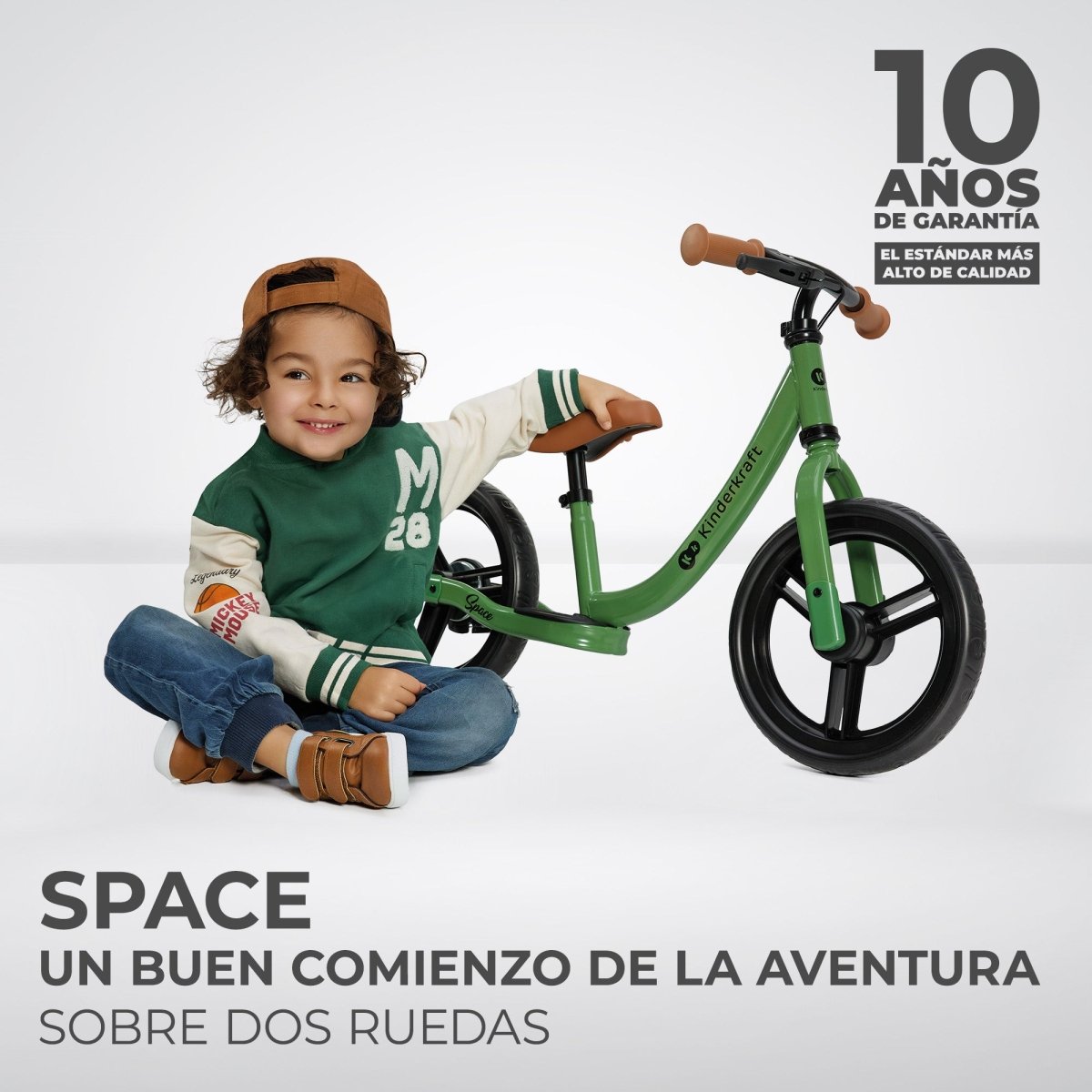 niño sentado junto a Bicicleta de equilibrio verde Space de Kinderkraft