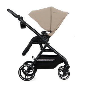 Coche cuna Yoxi 2 en 1 Kinderkraft color beige, vista lateral con la capota extendida y portavasos en el manillar