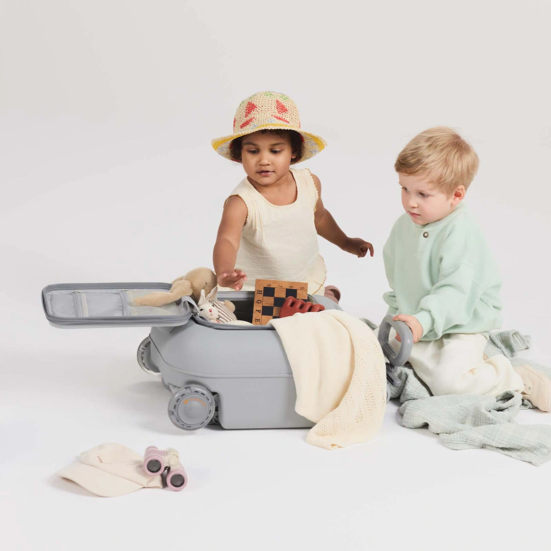 Niños jugando con la Maleta infantil 2 en 1 con asiento Cabby de Kinderkraft abierta y llena de juguetes