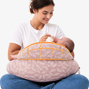 Cojín de lactancia NP008 de Momcozy rosa claro usado para dar mamadera con el bebé apoyado en el cojín