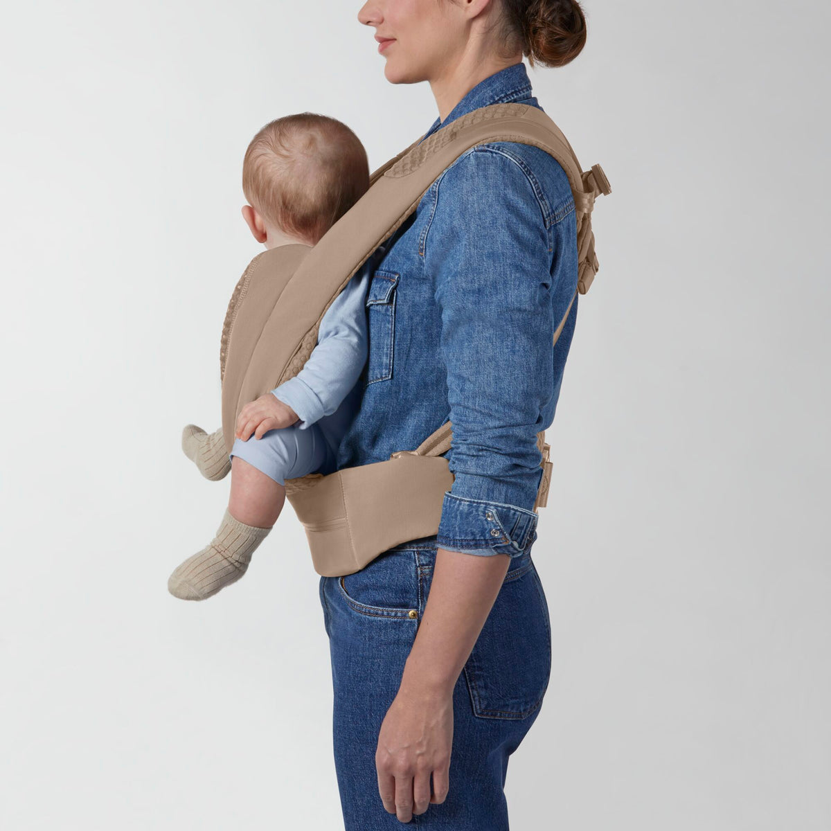 Portabebé Coÿa color Cozy Beige - vista lateral con bebé en posición de porteo en la espalda