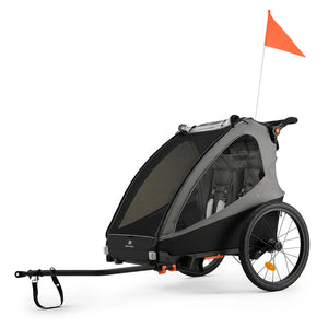 Remolque de bicicleta y coche de paseo Nava Walk 2 en 1 Kinderkraft en gris, vista lateral en modo remolque con bandera de seguridad naranja