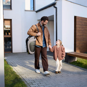 Hombre cargando la silla de auto Combinada Fix2Go i-Size Kinderkraft color gris topo sobre el hombro mientras camina de la mano con su hija