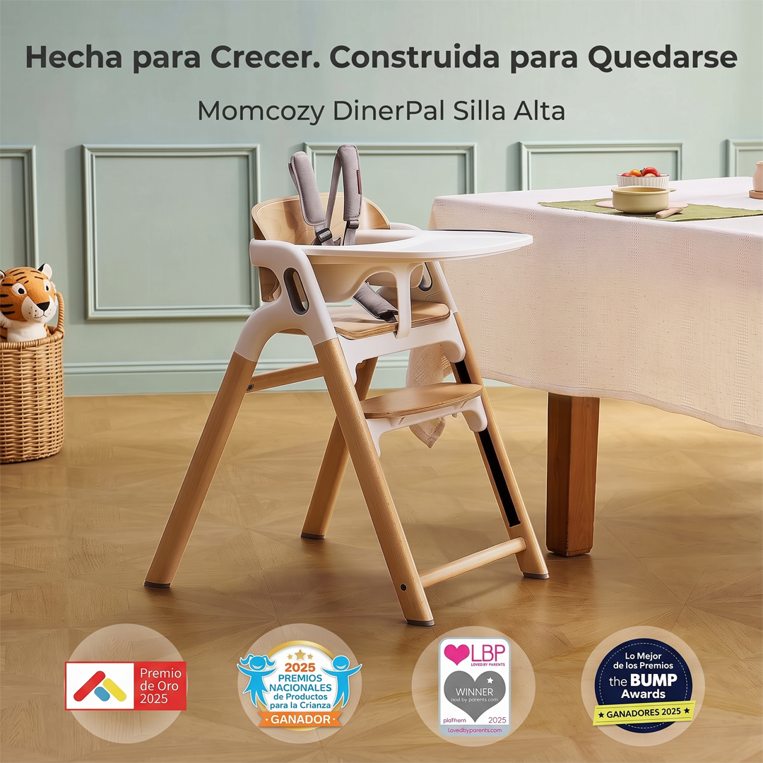 Silla de comer DinerPal Momcozy con bandeja y arnés junto a una mesa de comedor, con los sellos de premios 2025 Premio de Oro, Premios Nacionales de Productos para la Crianza, Loved by Parents y The Bump Awards