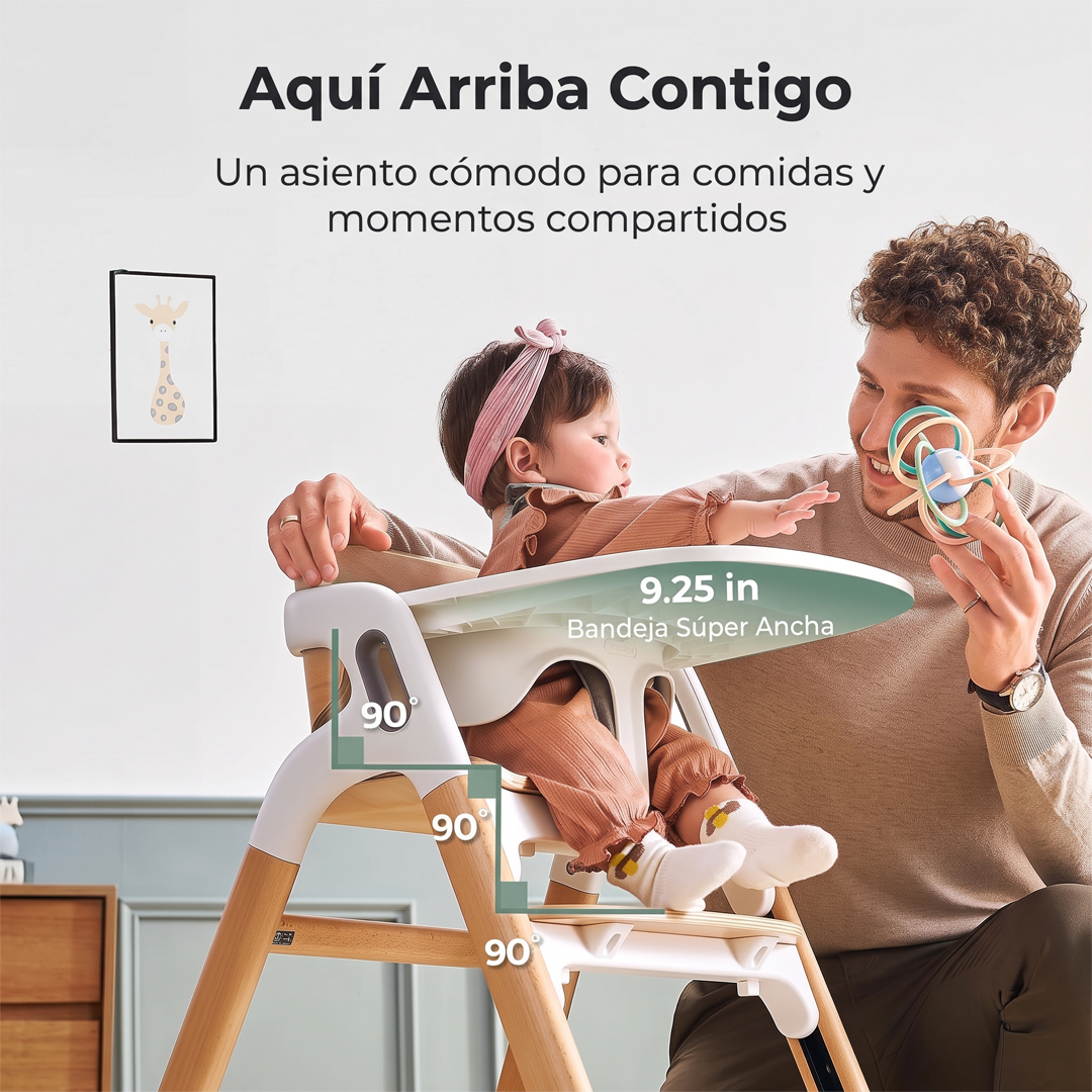 Bebé con cintillo rosado sentada en la silla DinerPal Momcozy junto a su papá, con ángulos de 90° en cadera, rodillas y tobillos y bandeja súper ancha de 9,25 pulgadas