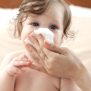 Mamá limpiando nariz de bebé con toallita salina Momcozy — solución salina natural suave para piel sensible