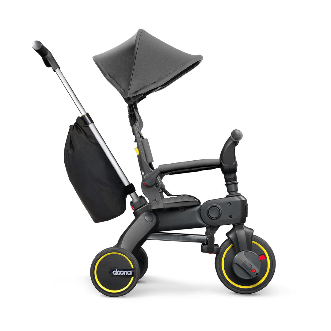Vista lateral del Liki Trike S3 Grey Hound con capota extendida y barra de empuje ajustada