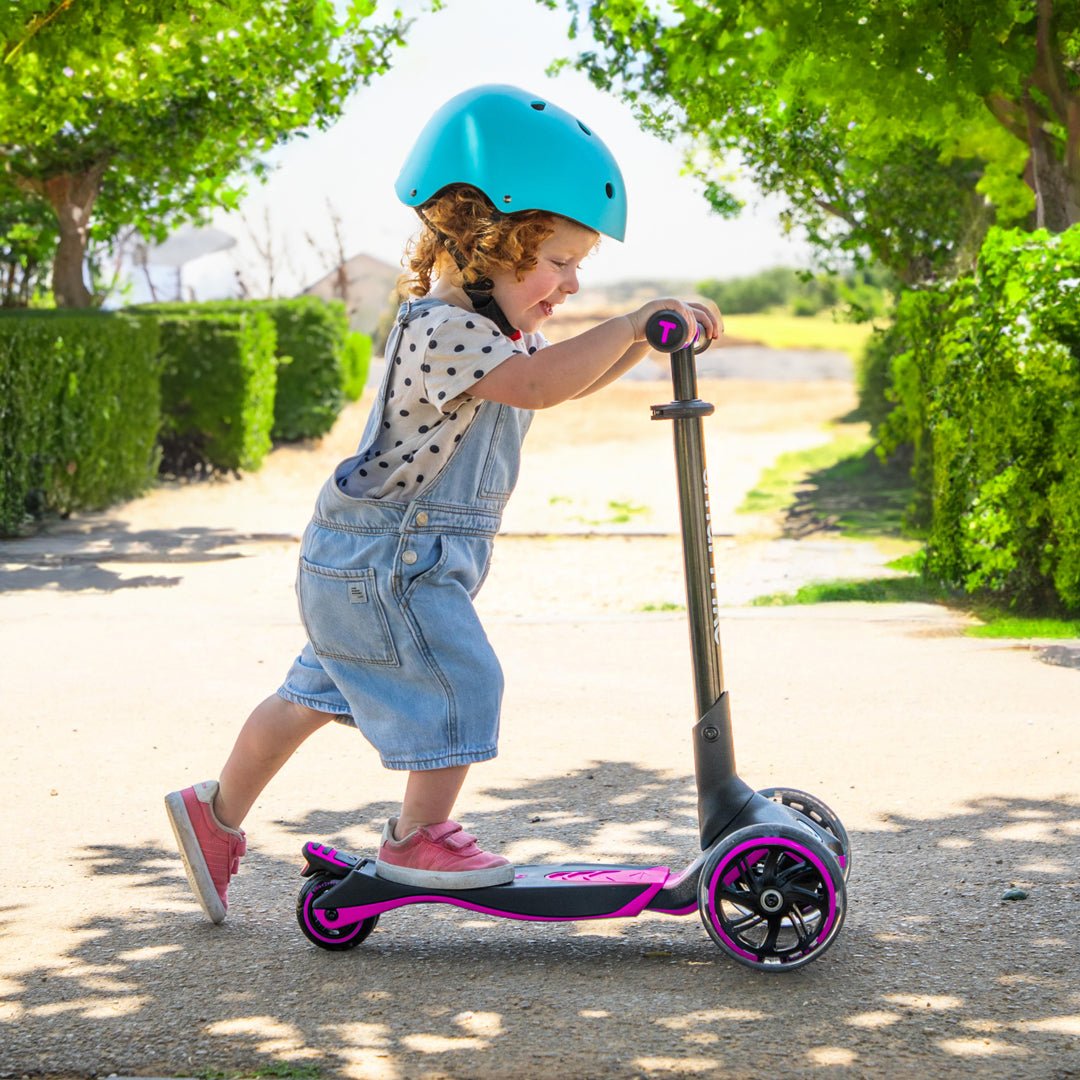 Bebé impulsándose en el SmarTrike Xtend Pink en etapa inicial al aire libre.