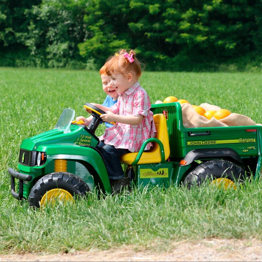 niños pequeños en Vehiculo electrico John Deere Gator HPX de Peg Perego en un campo